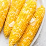 A plate of smoked corn on the cob with butter on top.