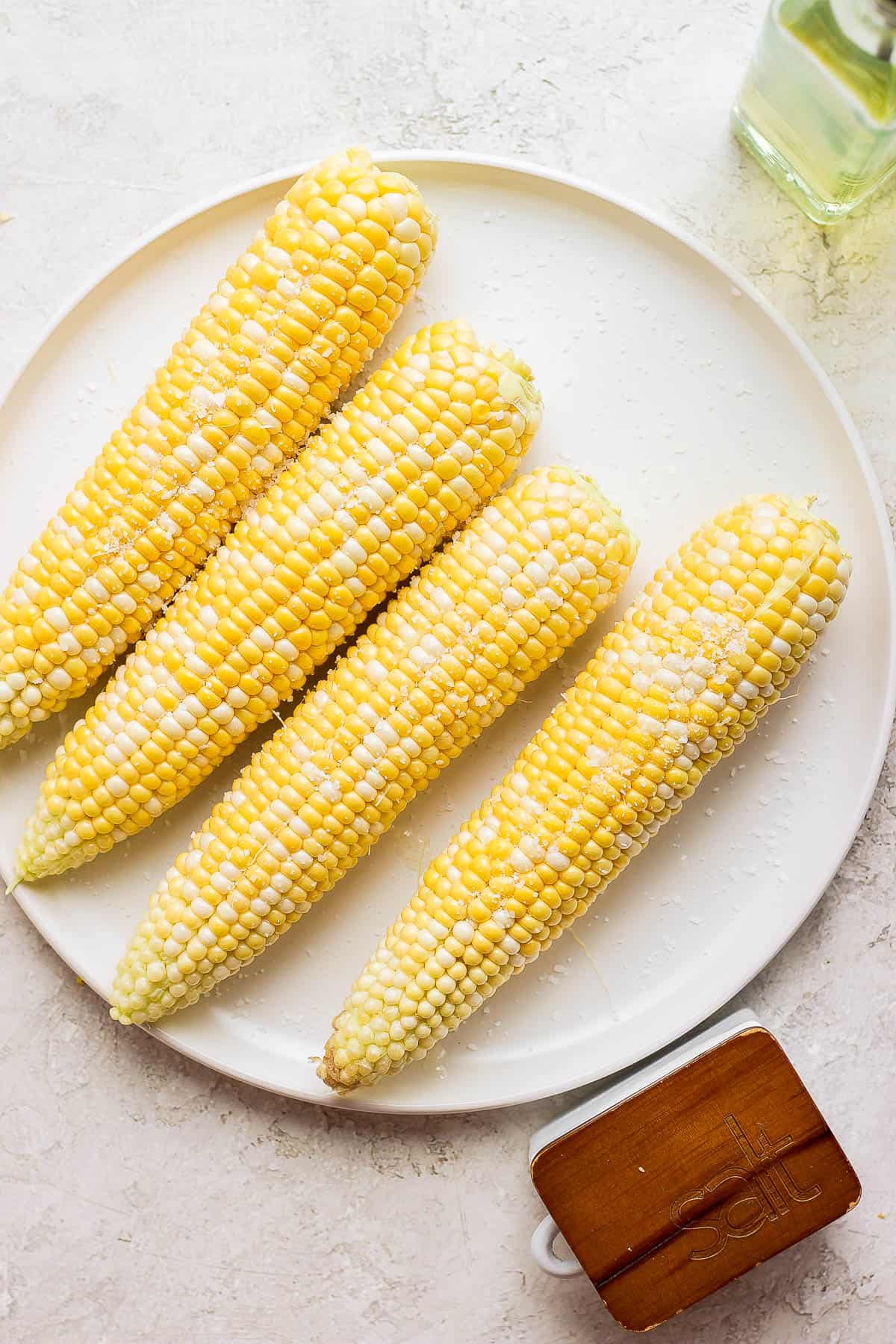 Plate of raw corn rubbed with oil and salt on top. 