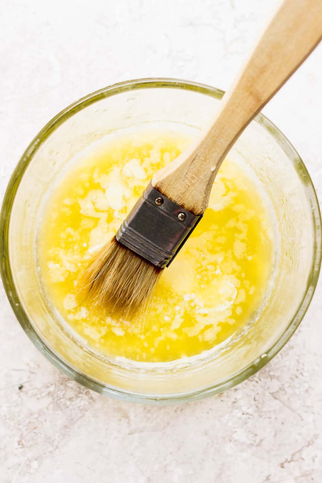 Bowl of melted butter with brush sticking out. 