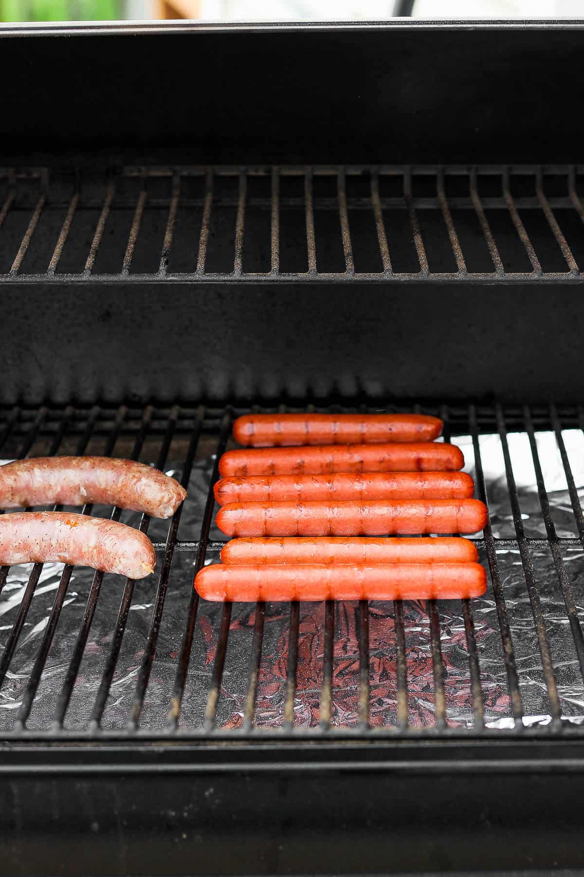 Farther away shot of hot dogs on a smoker. 
