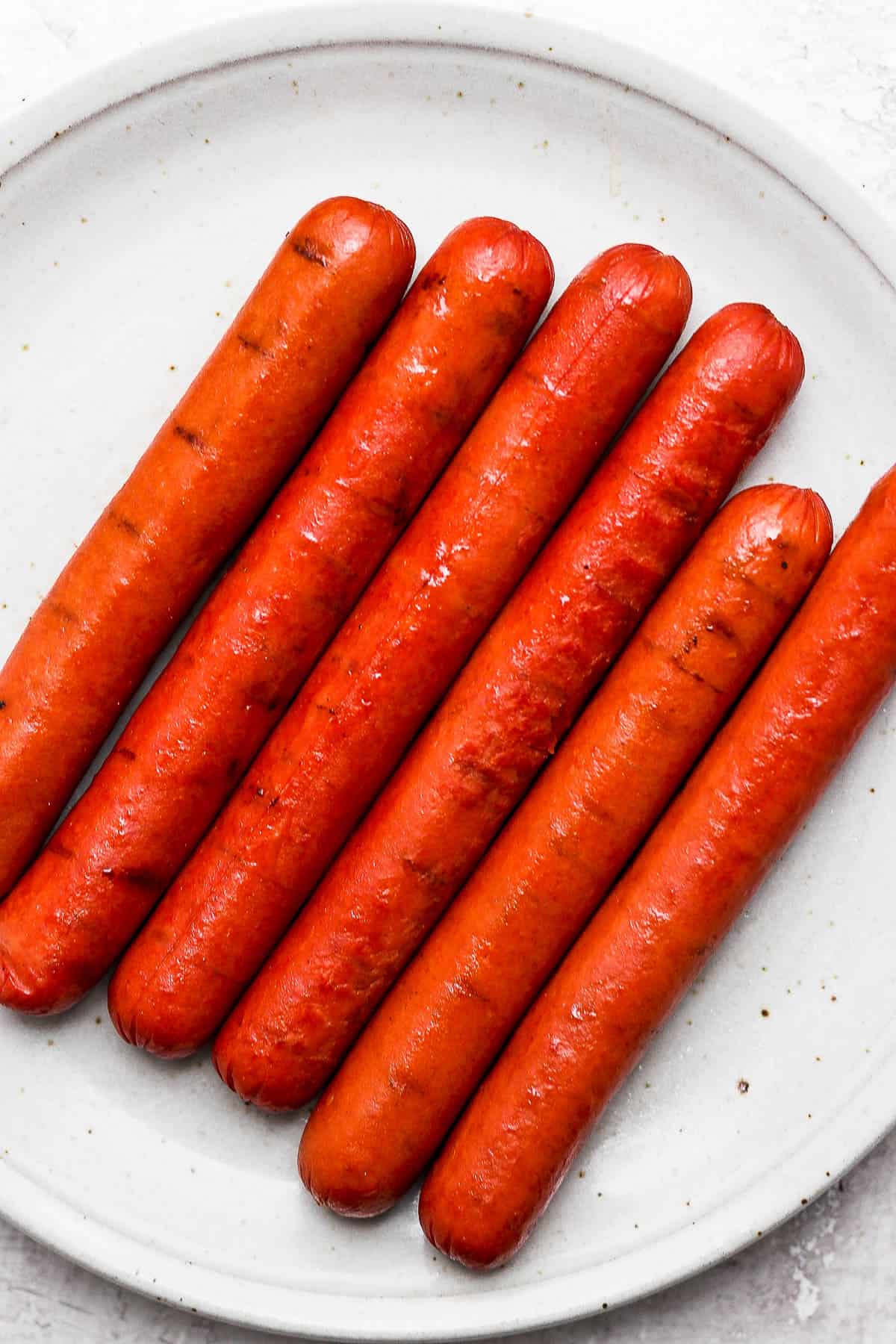 Smoked hot dogs resting on a plate.