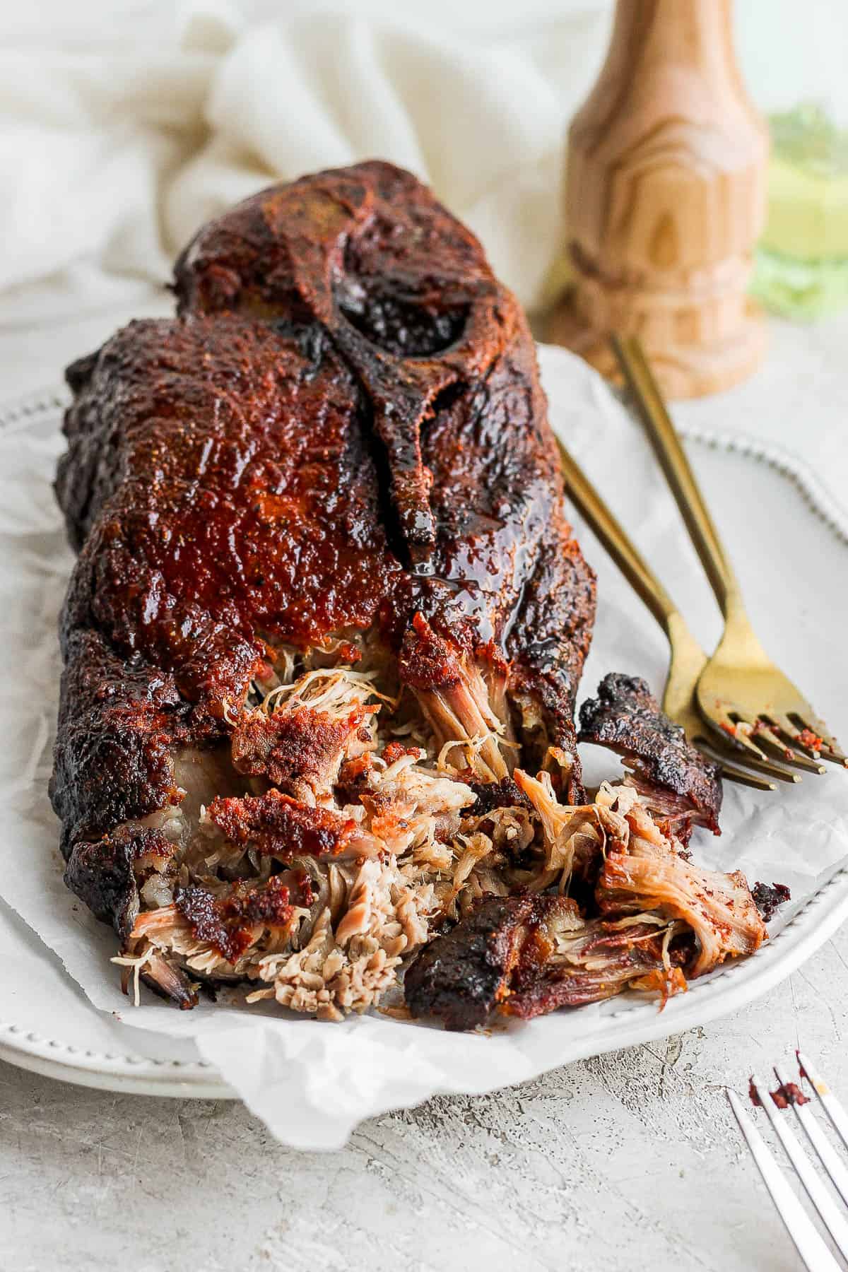 A smoked pork butt on a plate with the front portion shredded.