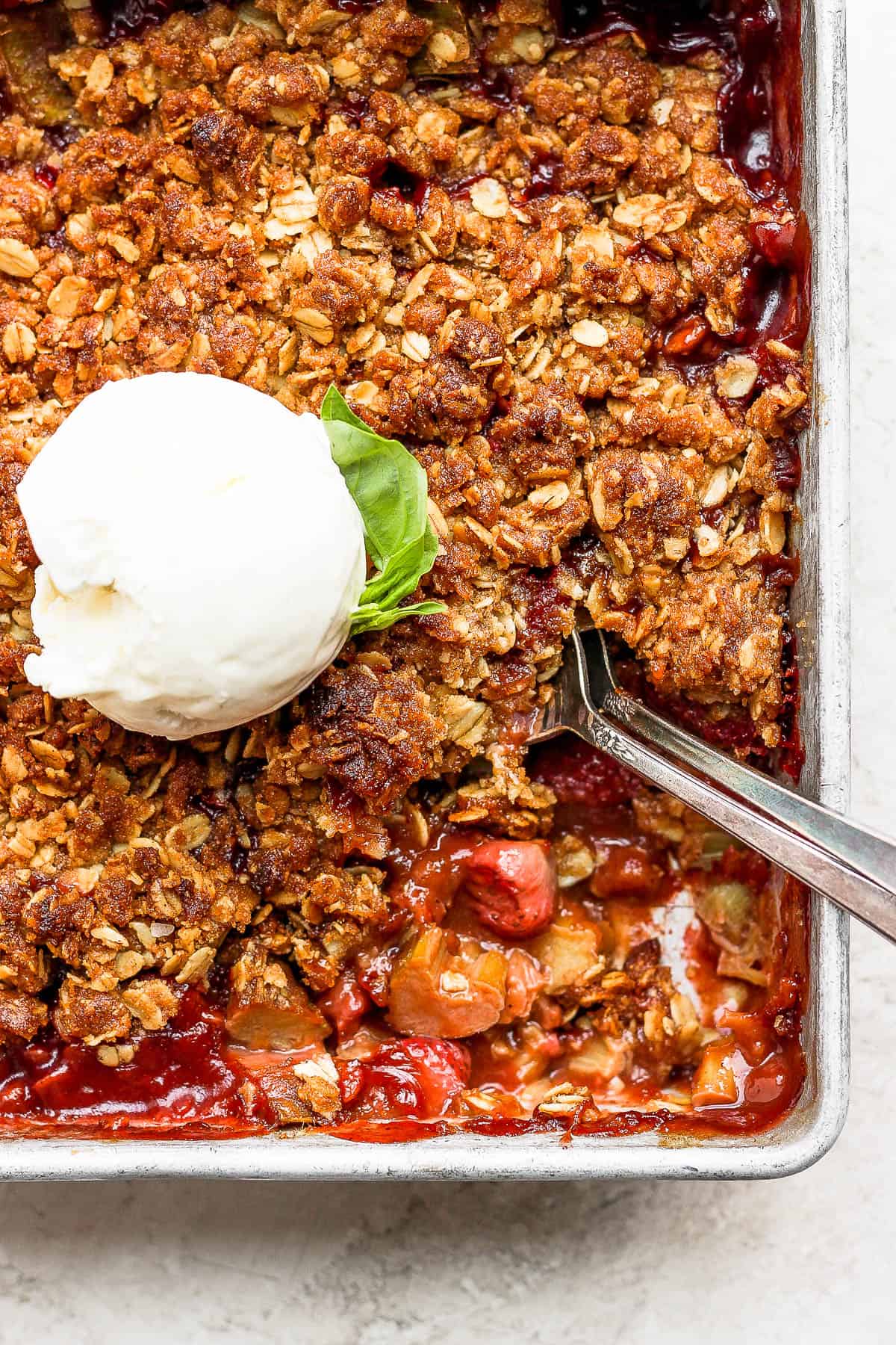 Strawberry rhubarb crisp topped with a scoop of vanilla ice cream.