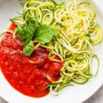 A bowl of zucchini spaghetti with fresh basil garnish.