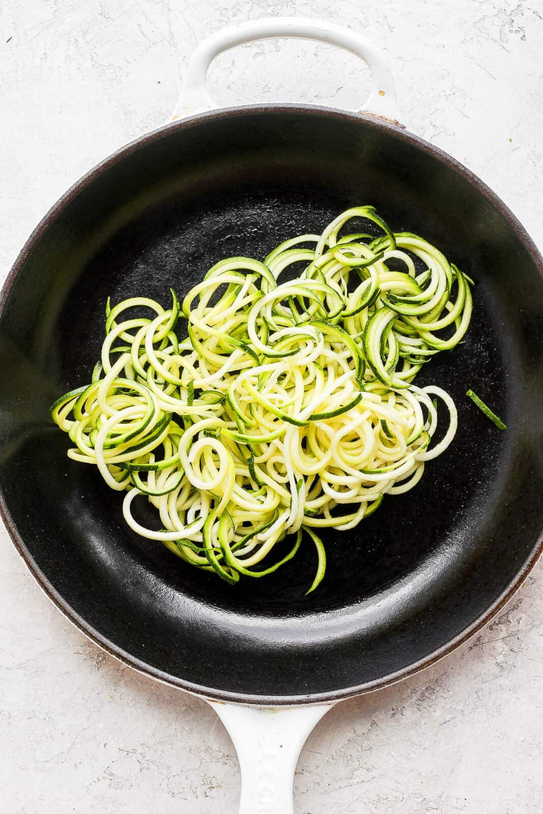 Zoodles sautéing in a skillet.