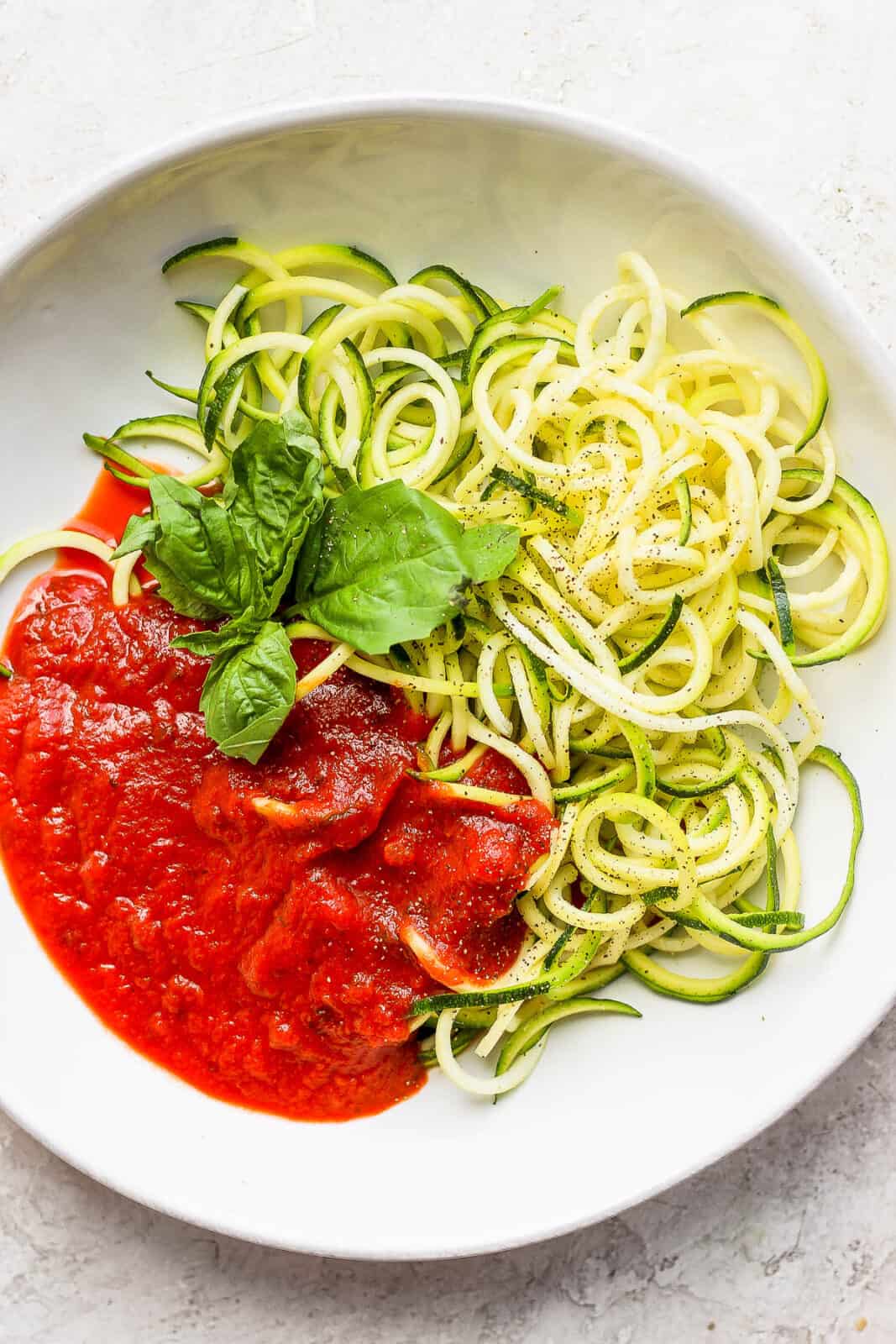 Zucchini noodles and pasta sauce in a bowl.