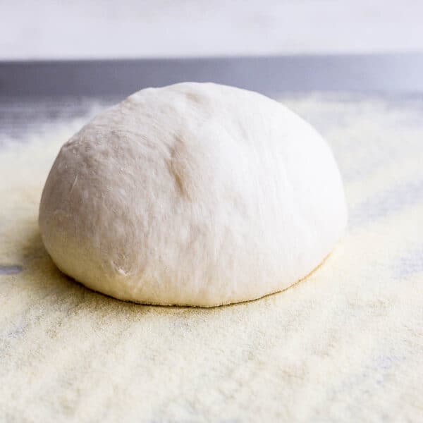 Homemade pizza dough in a ball on some semolina flour.