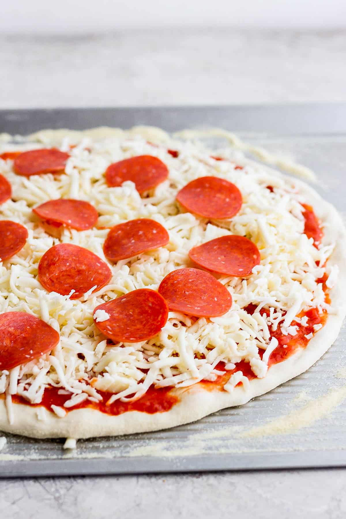 Pizza dough with sauce, cheese, and pepperoni on top.