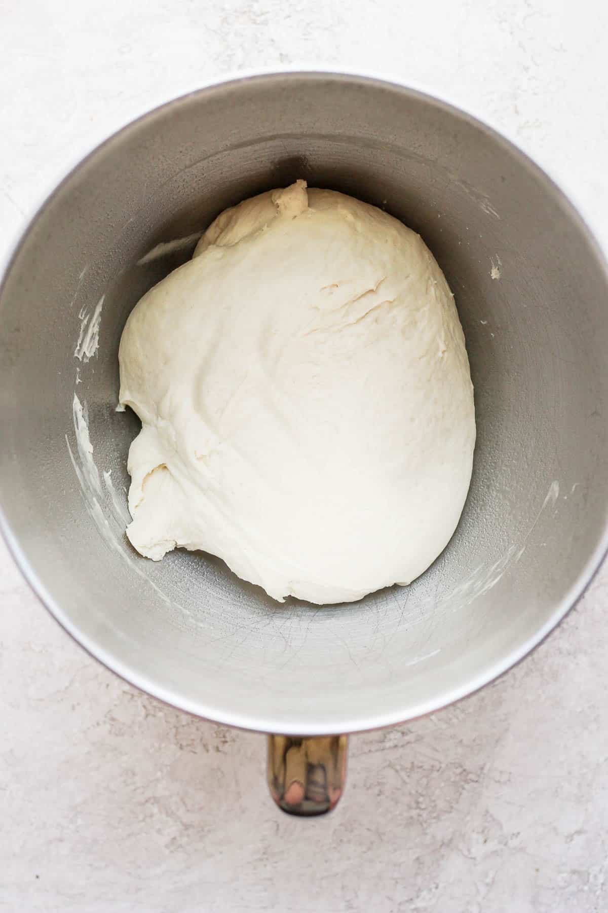 Pizza dough in a bowl sprayed with non-stick spray.