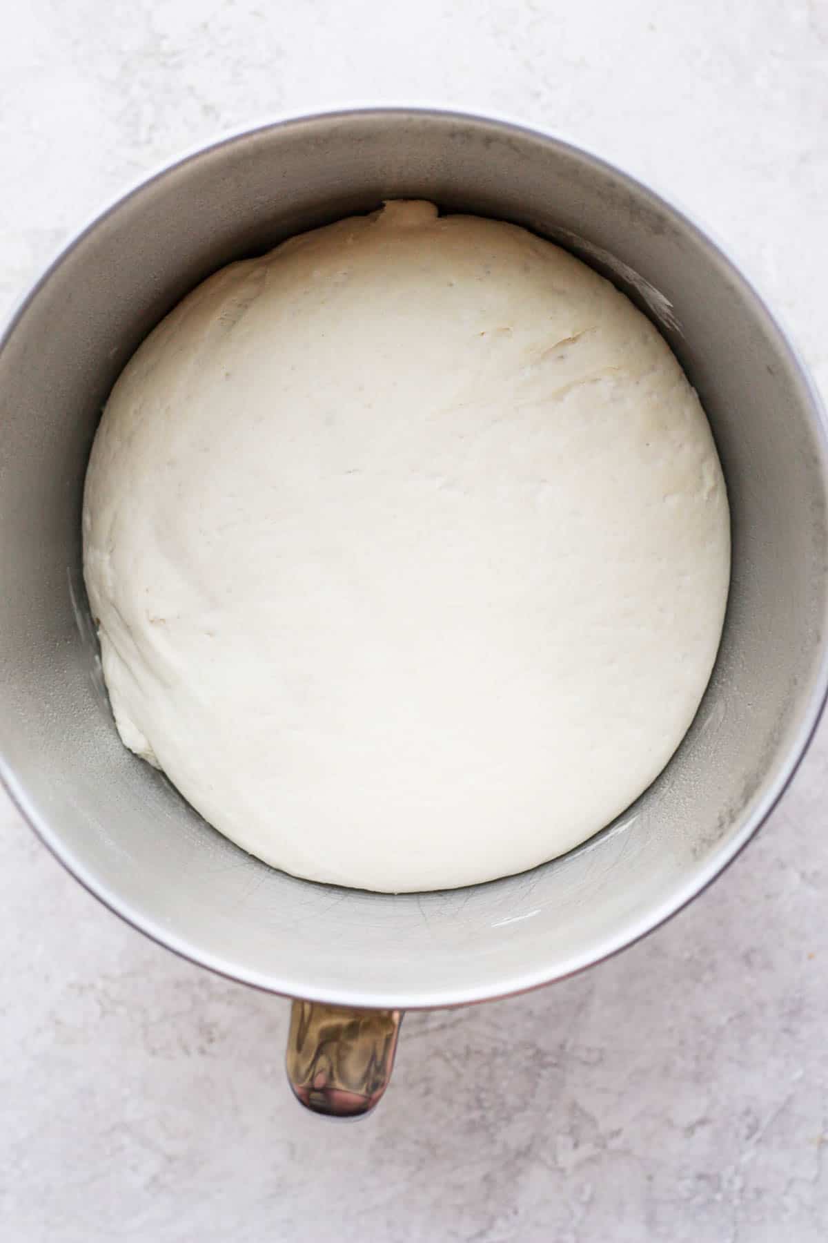 Pizza dough still in the same metal bowl but doubled in size.