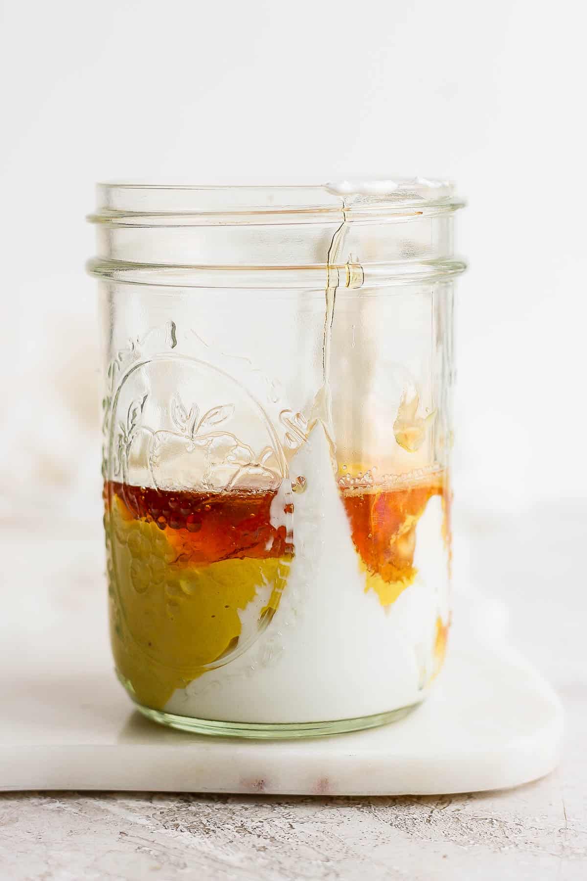 Honey mustard dressing ingredients in a mason jar.