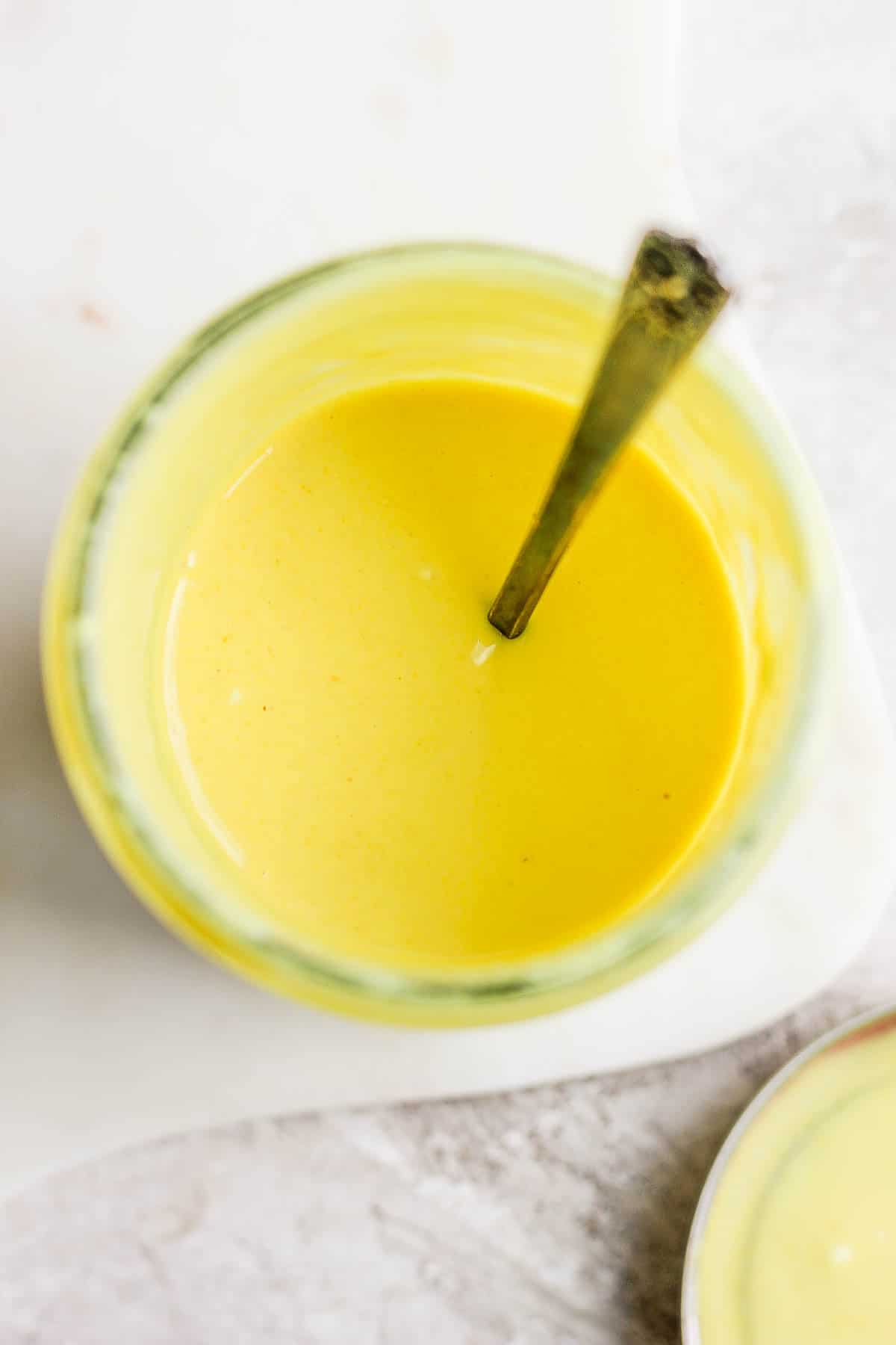 Honey mustard salad dressing in a jar with a spoon.