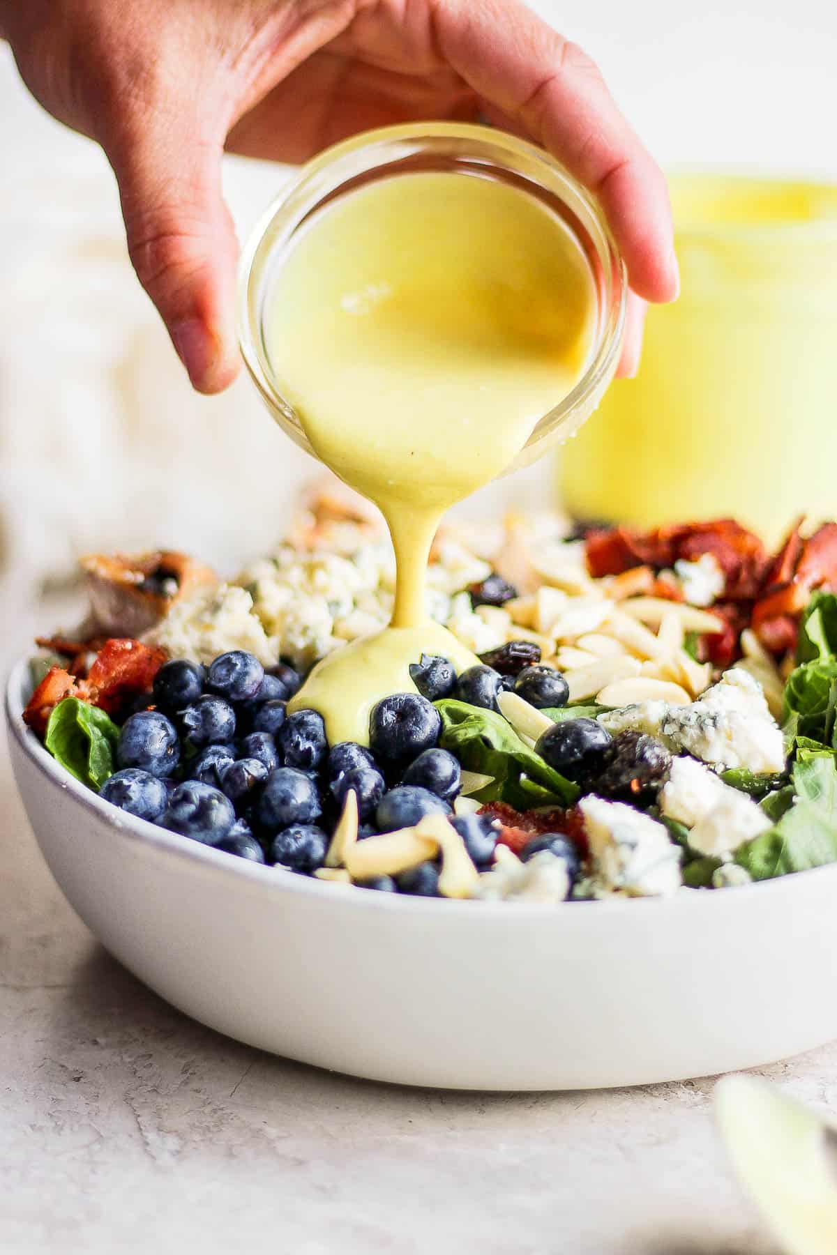 Honey mustard dressing being poured on the salad.