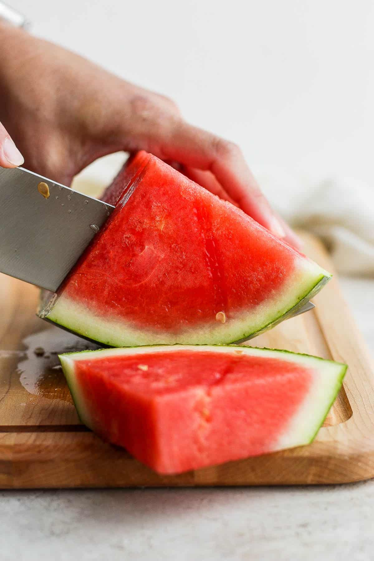 A quarter of a watermelon being cut into 1 inch triangle slices.