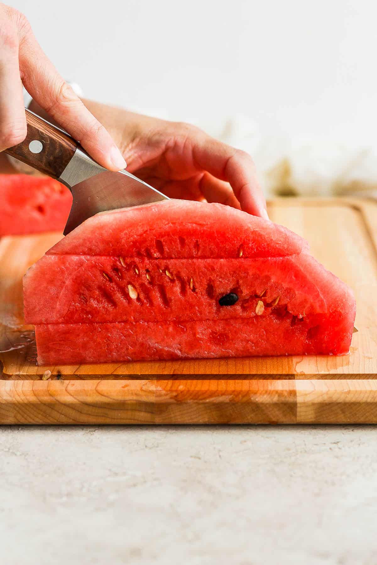 A quarter of a watermelon being cut into sticks.
