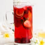 A pitcher of cold brew tea with strawberries inside.