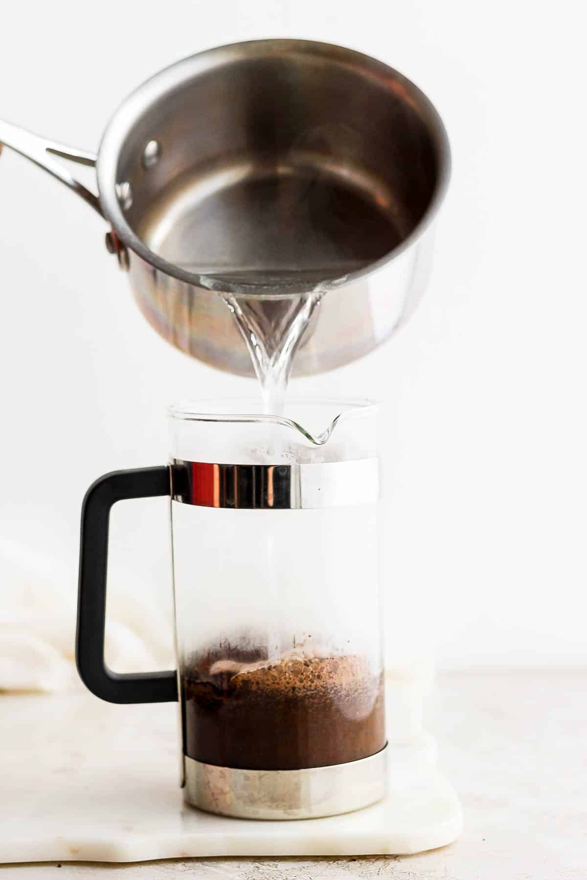 Someone pouring hot water into a french press.