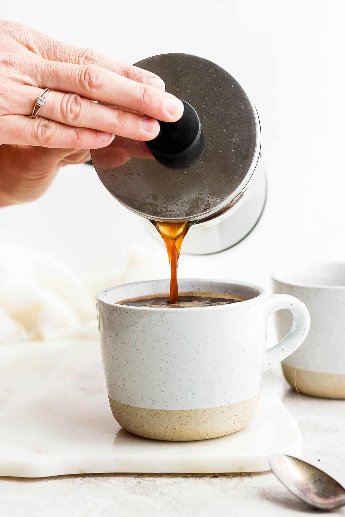 Someone pouring coffee out of a french press into a mug.