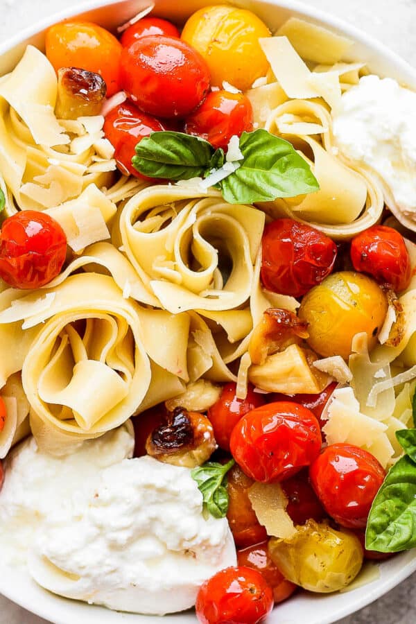 Bowl of late summer pasta with burrata, fresh basil and tomatoes.