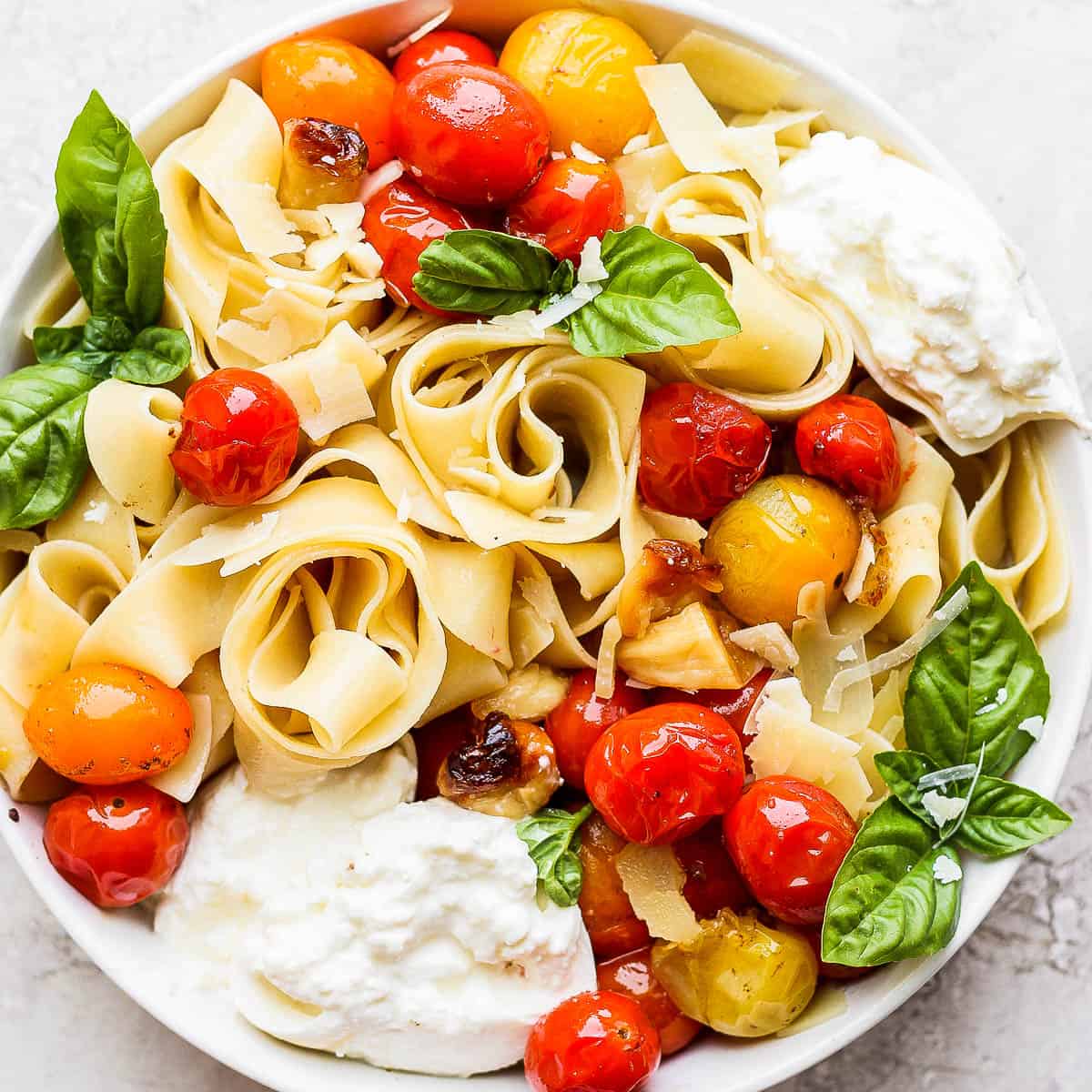 Bowl of late summer pasta with burrata, fresh basil and tomatoes.