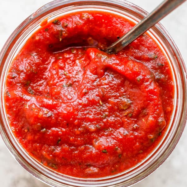 Top shot of a jar of homemade pizza sauce with a spoon sticking out.