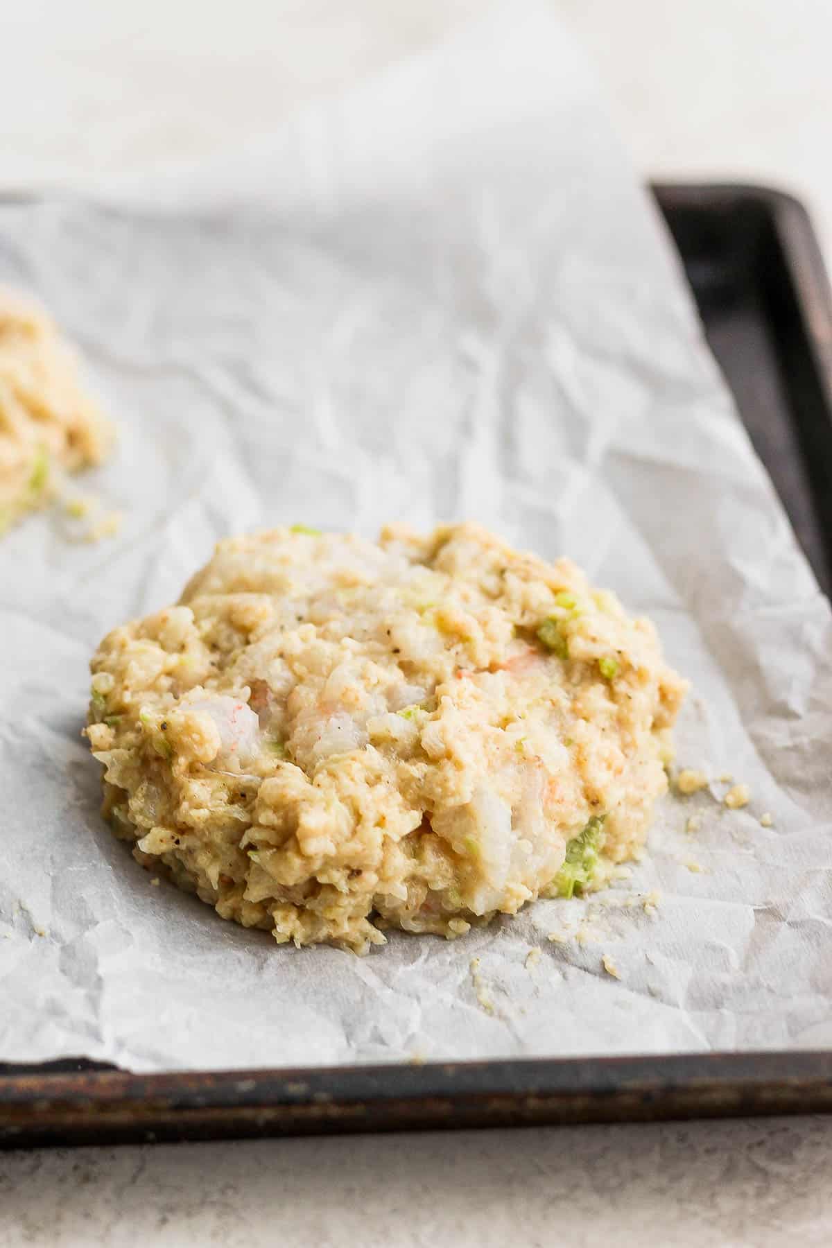 Shrimp burger patties on a parchment-lined pan.