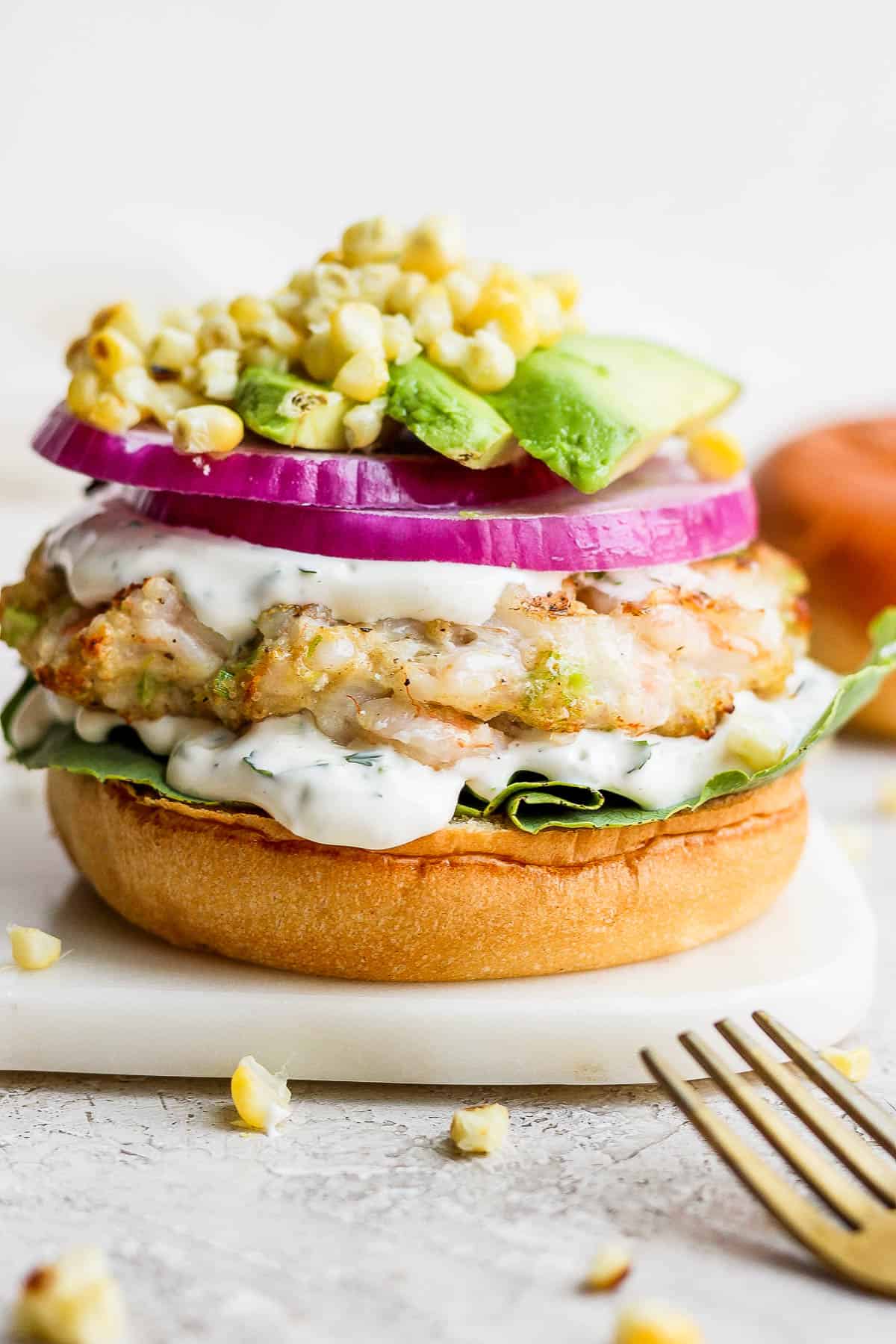 A shrimp burger with toppings being added.