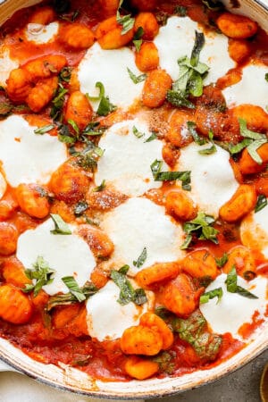 Big pan of baked gnocchi with melted mozzarella cheese and fresh basil.