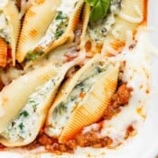 A close up of the corner of a pan of baked shells with meat.