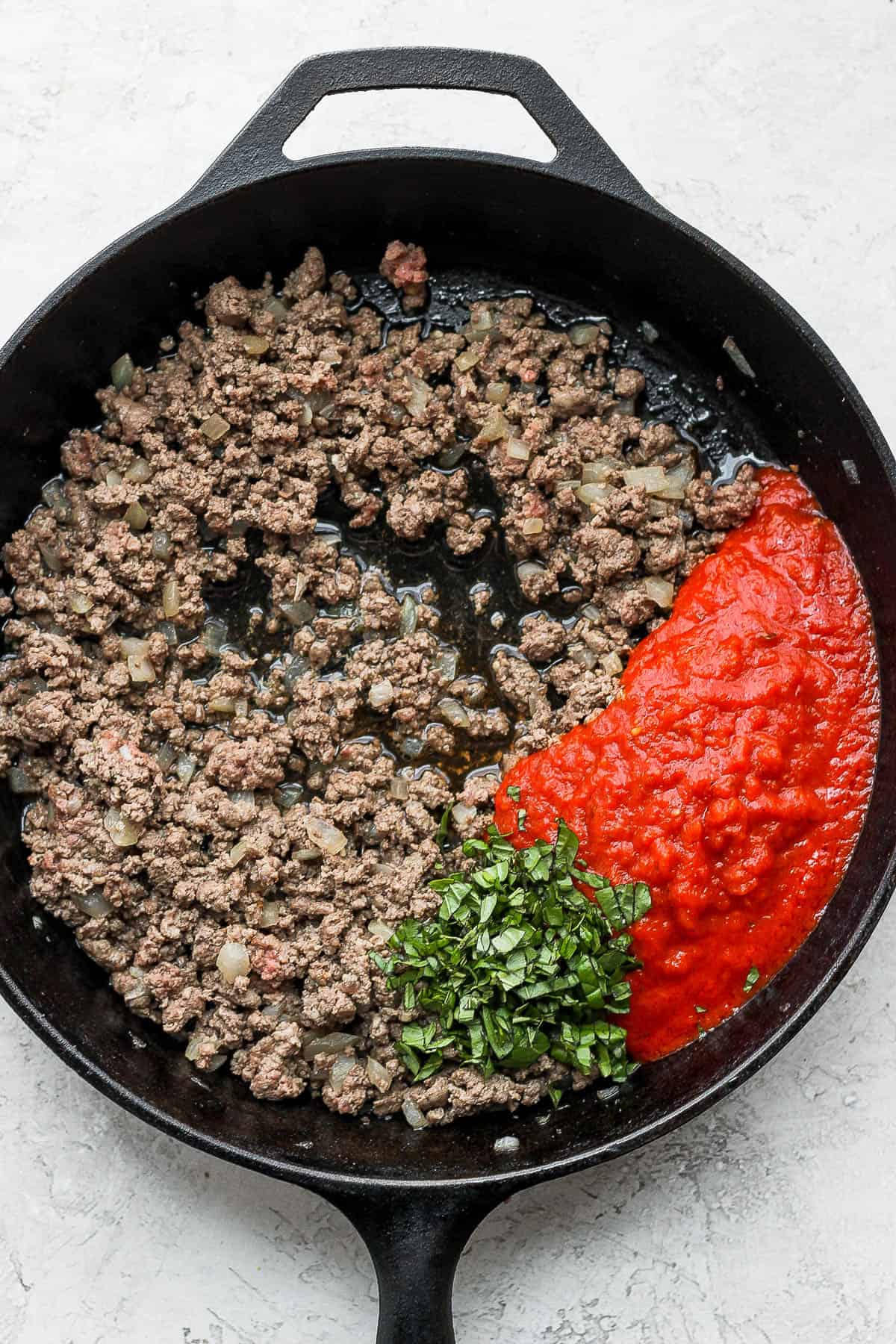Ground beef, onion, garlic, olive oil, chopped basil, salt, pepper, and marinara sauce in a cast iron skillet. 