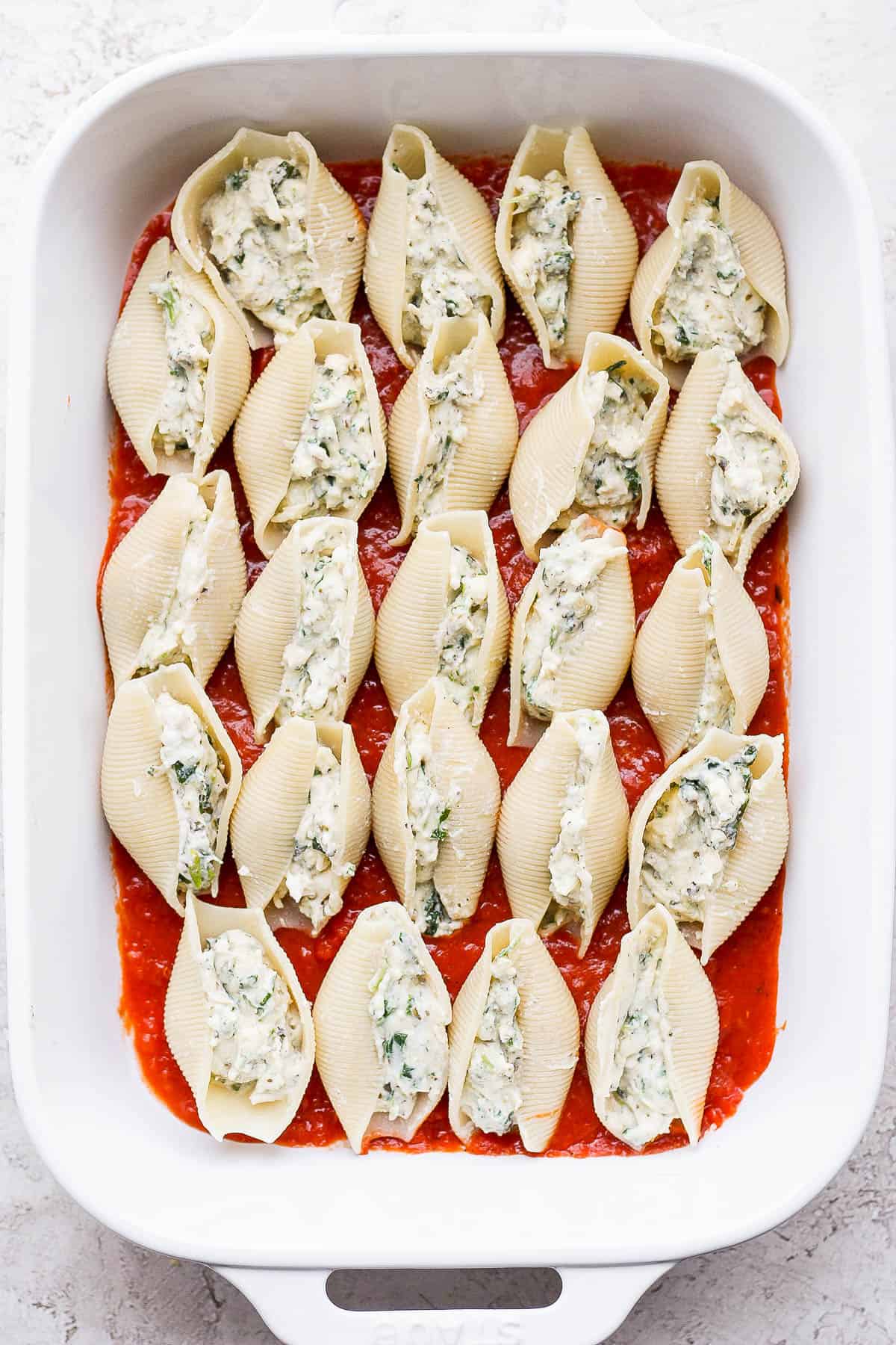 Pasta shells filled with ricotta mixture placed on top of meat sauce in the 9x13 baking dish. 