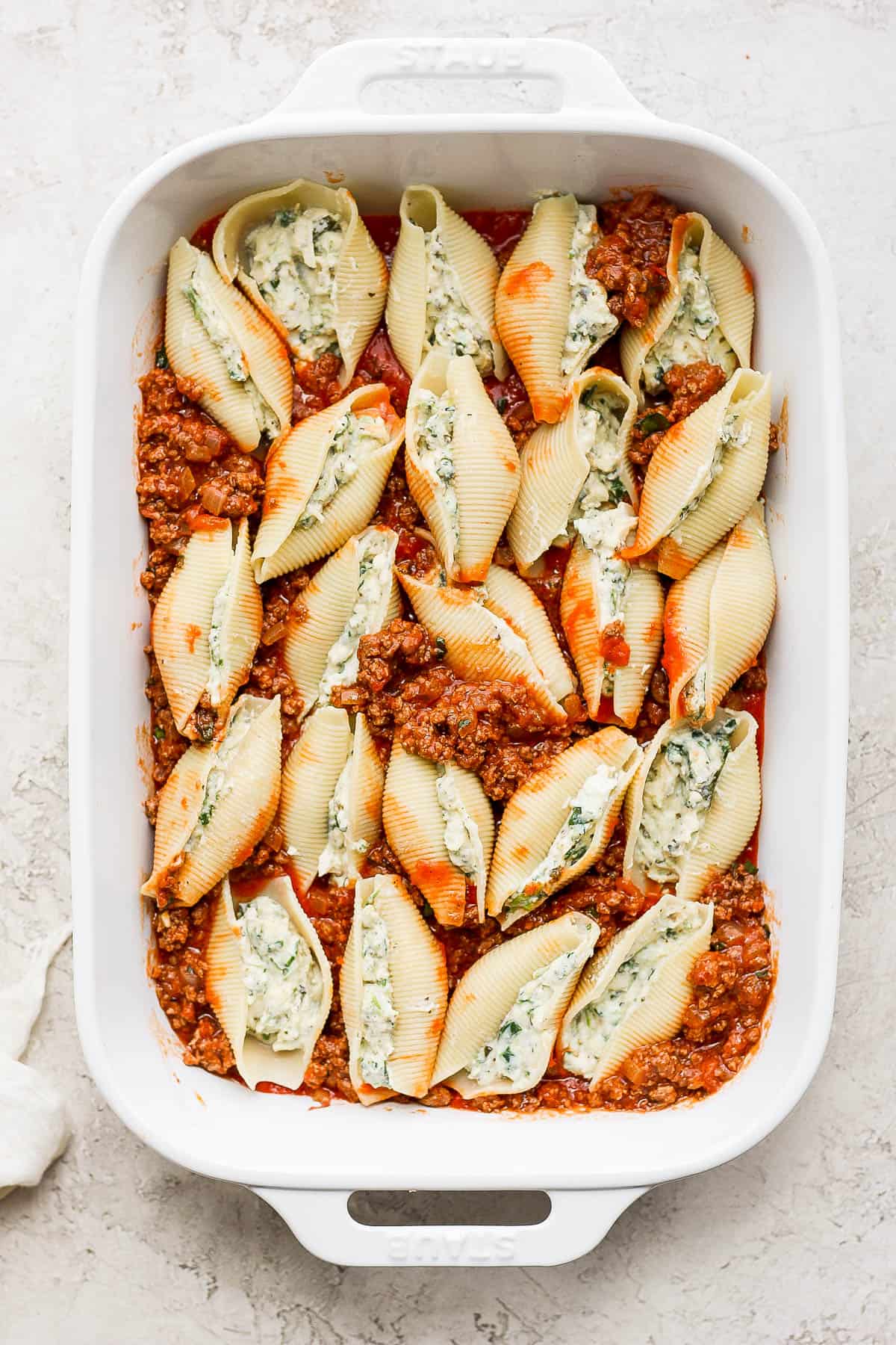 Stuffed pasta shells covered with remaining meat sauce in 9x13 baking dish. 