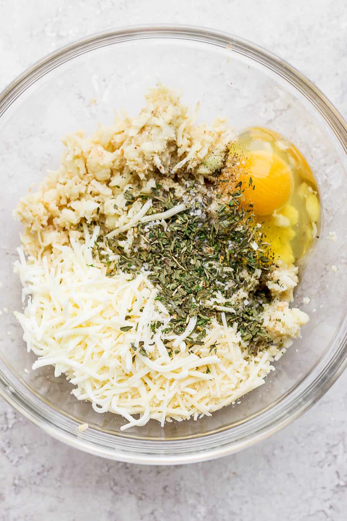 All ingredients for a cauliflower pizza crust in a bowl.