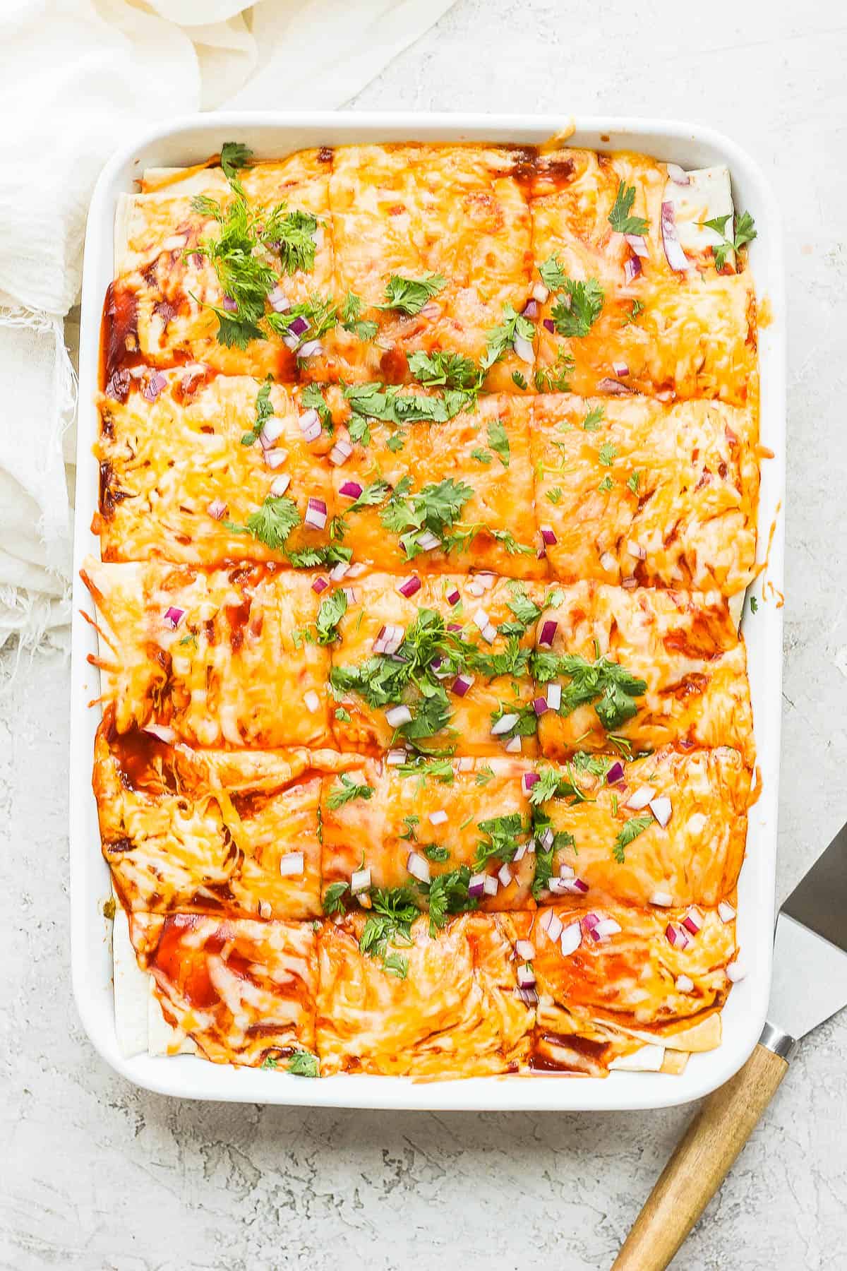 The baked chicken enchilada casserole with fresh cilantro and red onion on top.