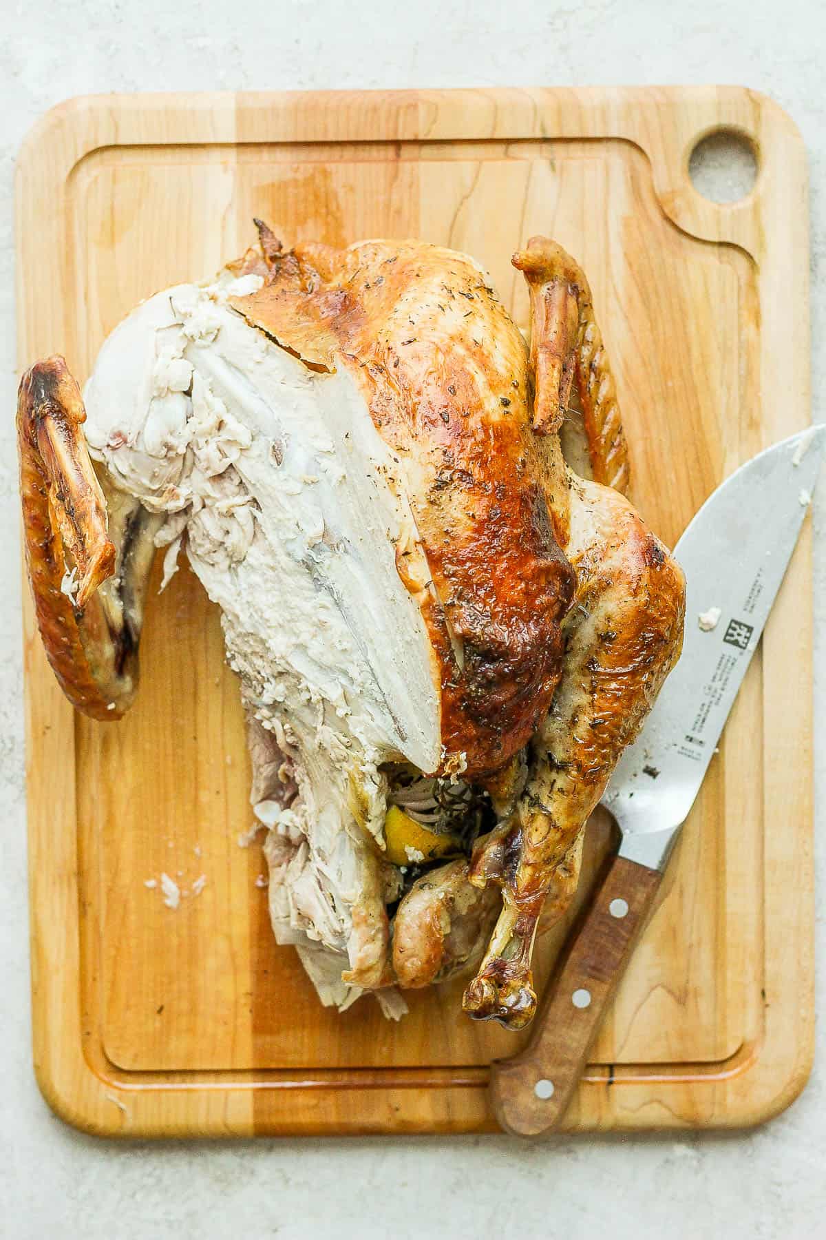 One leg and breast fully removed from the turkey carcass.