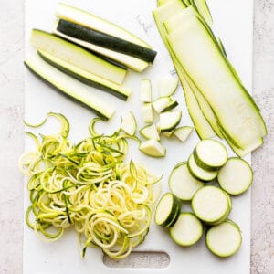 A cutting board showing 5 different ways to cut zucchini.