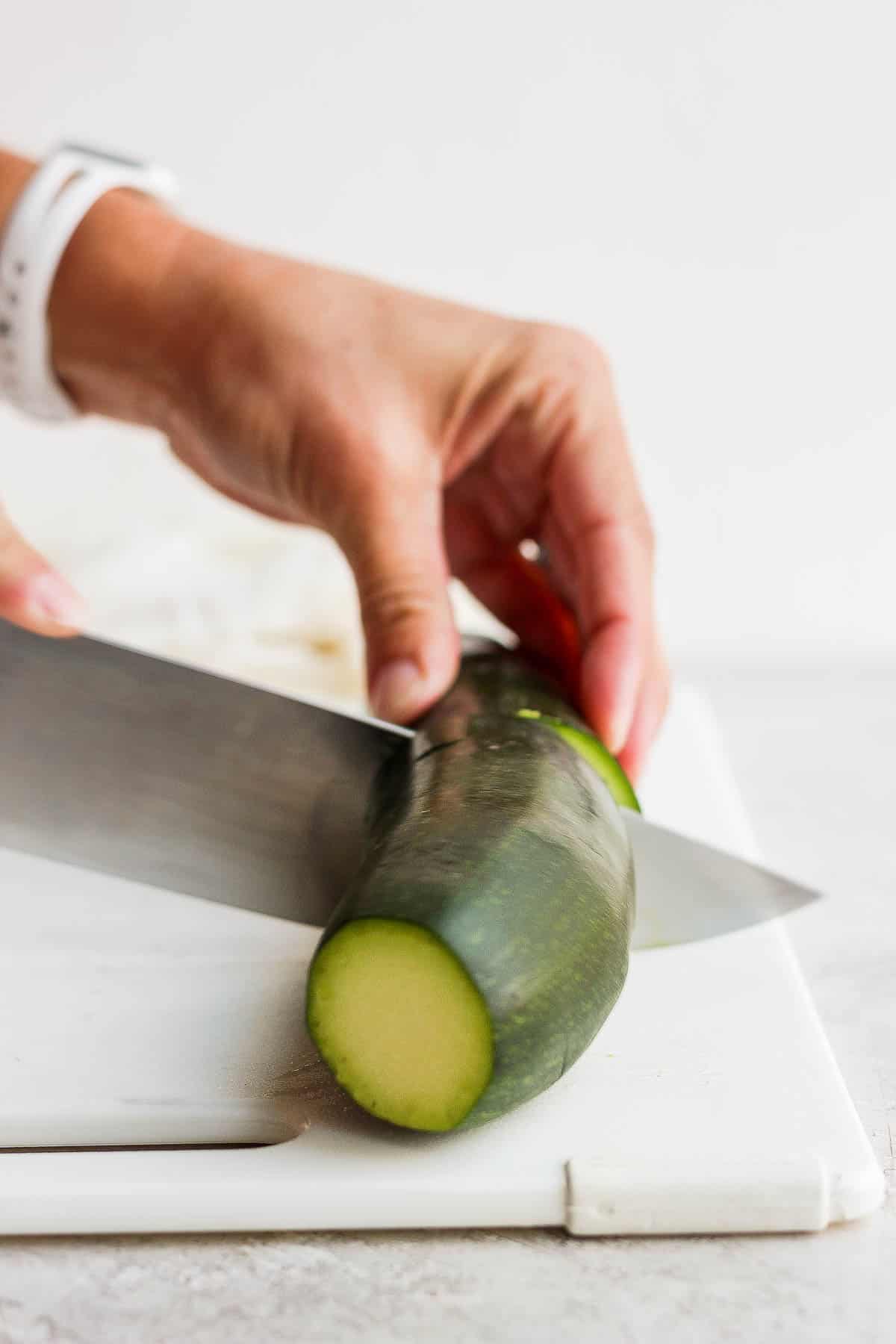 A zucchini being cut in half, widthwise.