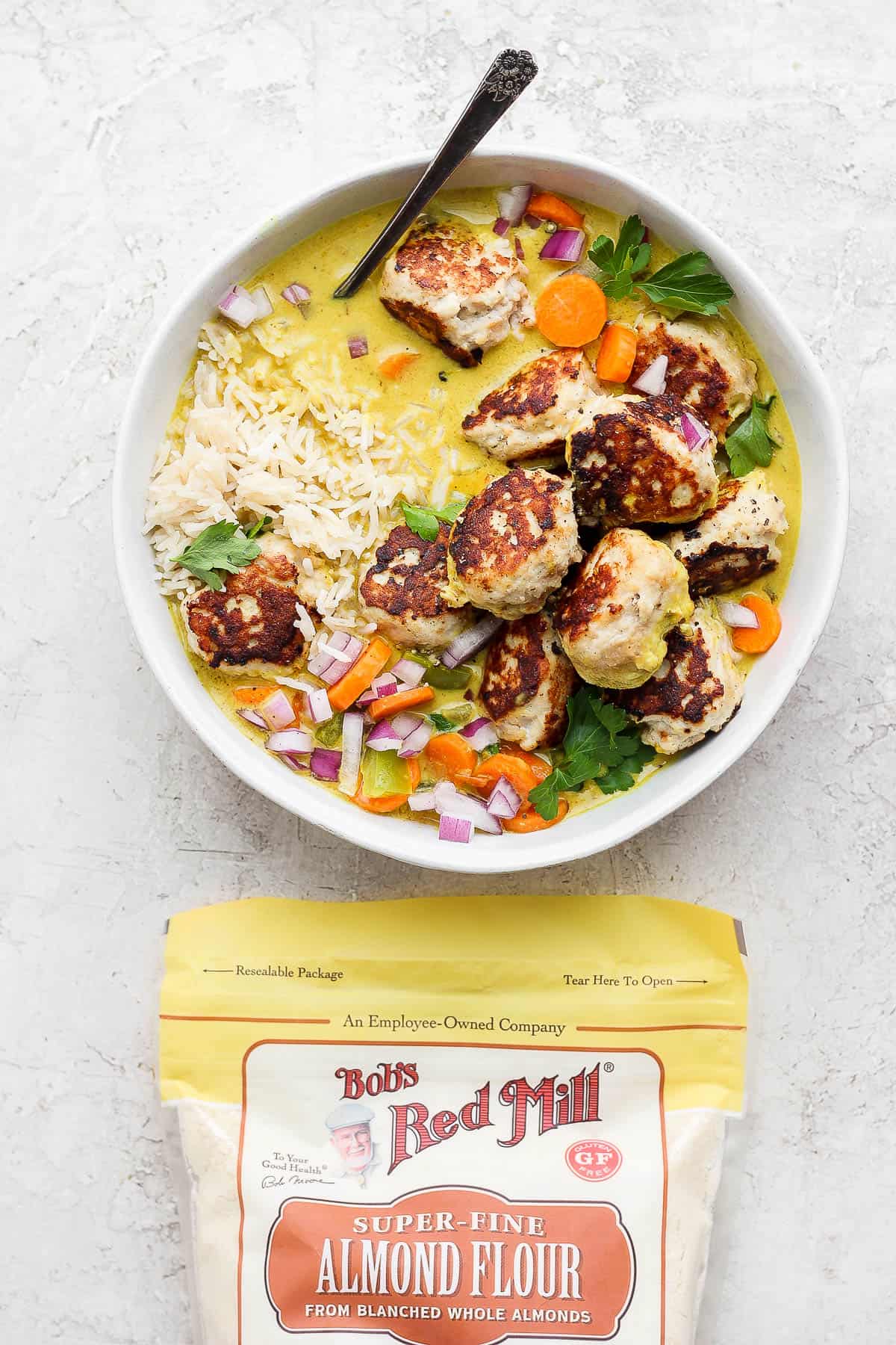 Meatball curry in a bowl with a bag of Bob's Red Mill almond flour.