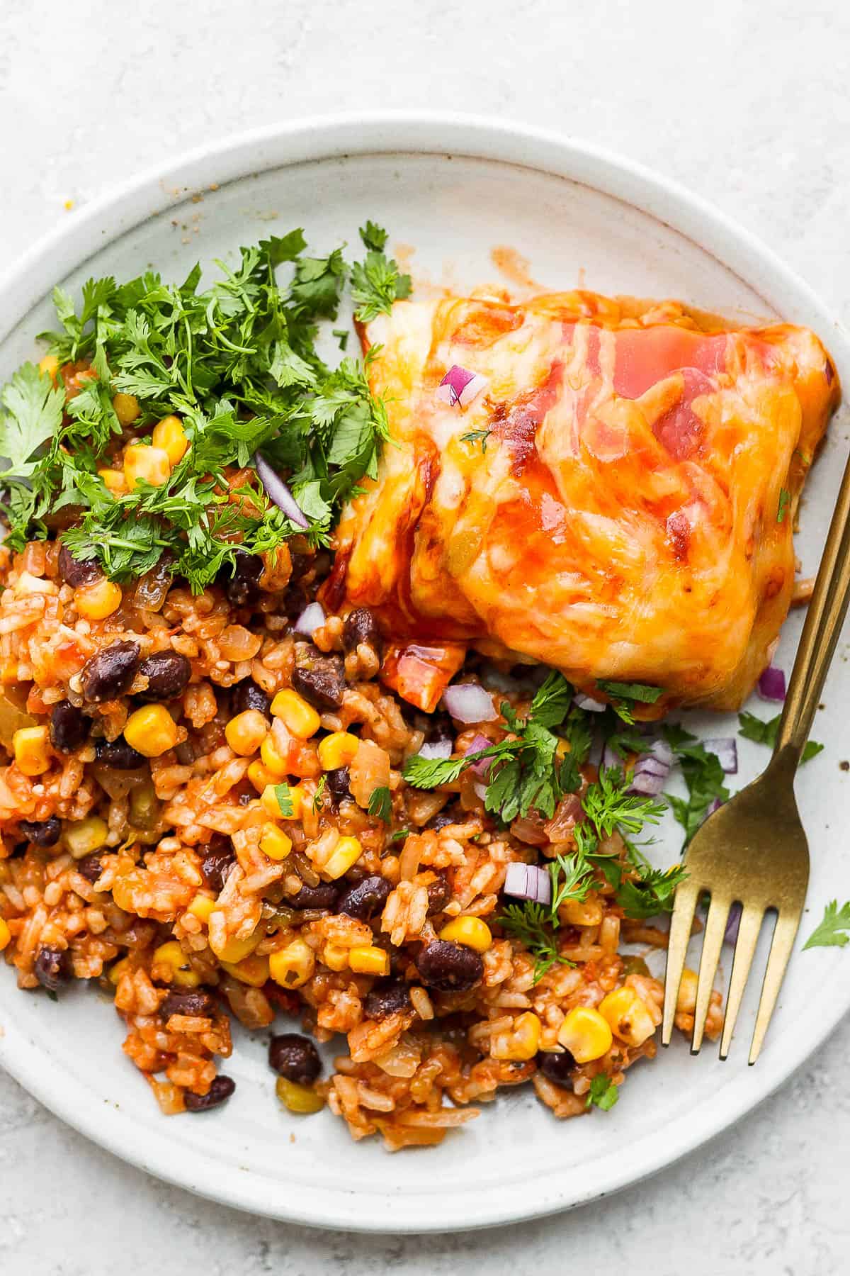 Salsa rice on a plate with chicken enchilada casserole and a fork.