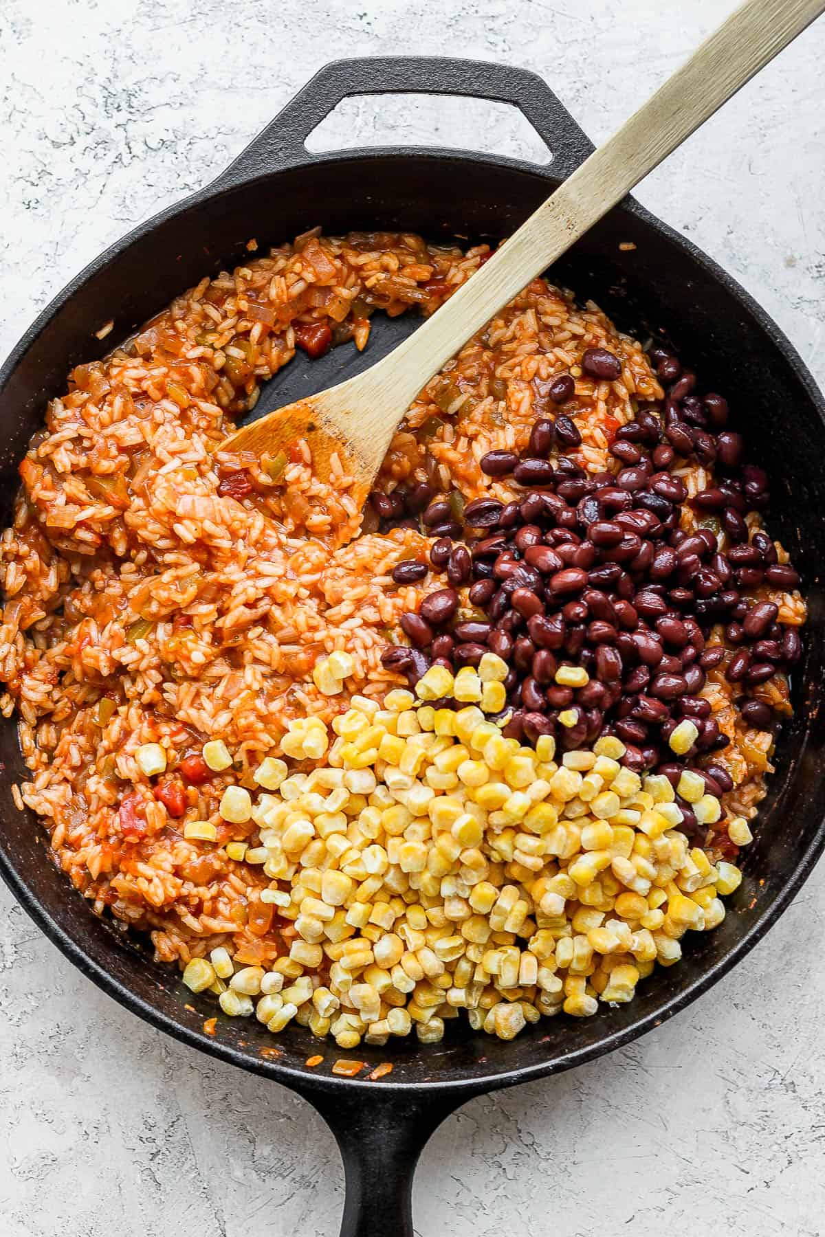 Fully cooked salsa rice with beans and corn being added.