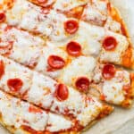 A smoked pizza on a piece of parchment cut into squares.