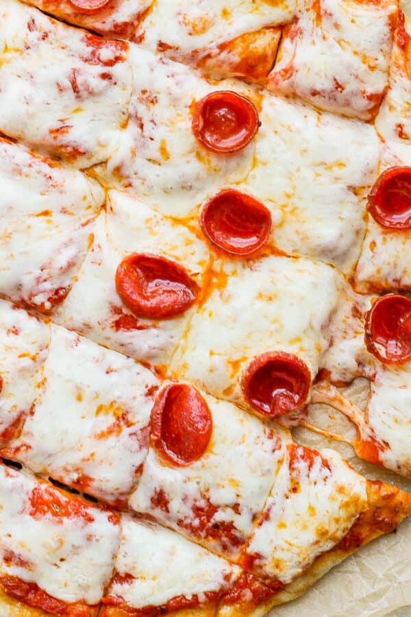 A smoked pizza on a piece of parchment cut into squares.