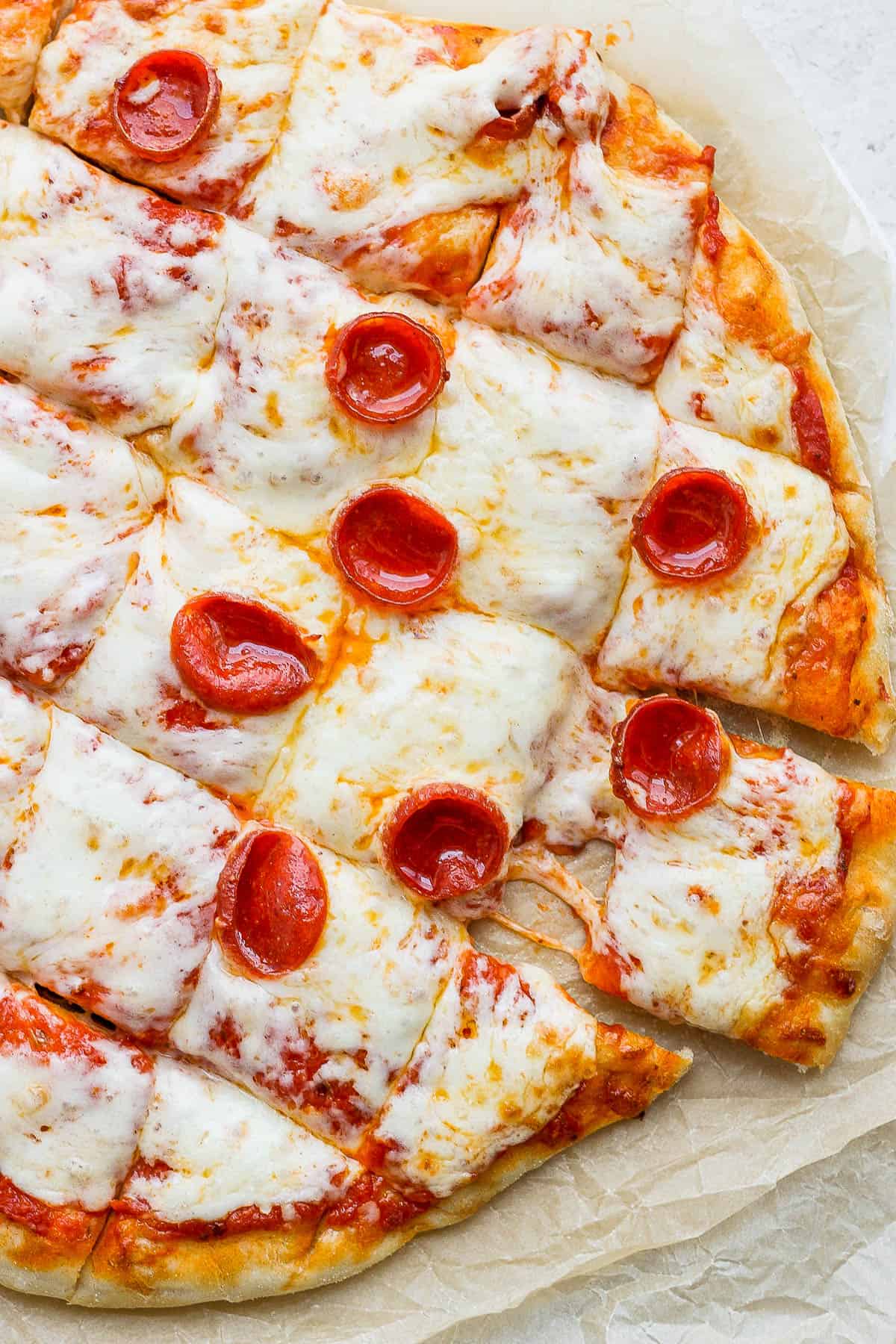 A smoked pizza cut into squares with pepperoni on top. 