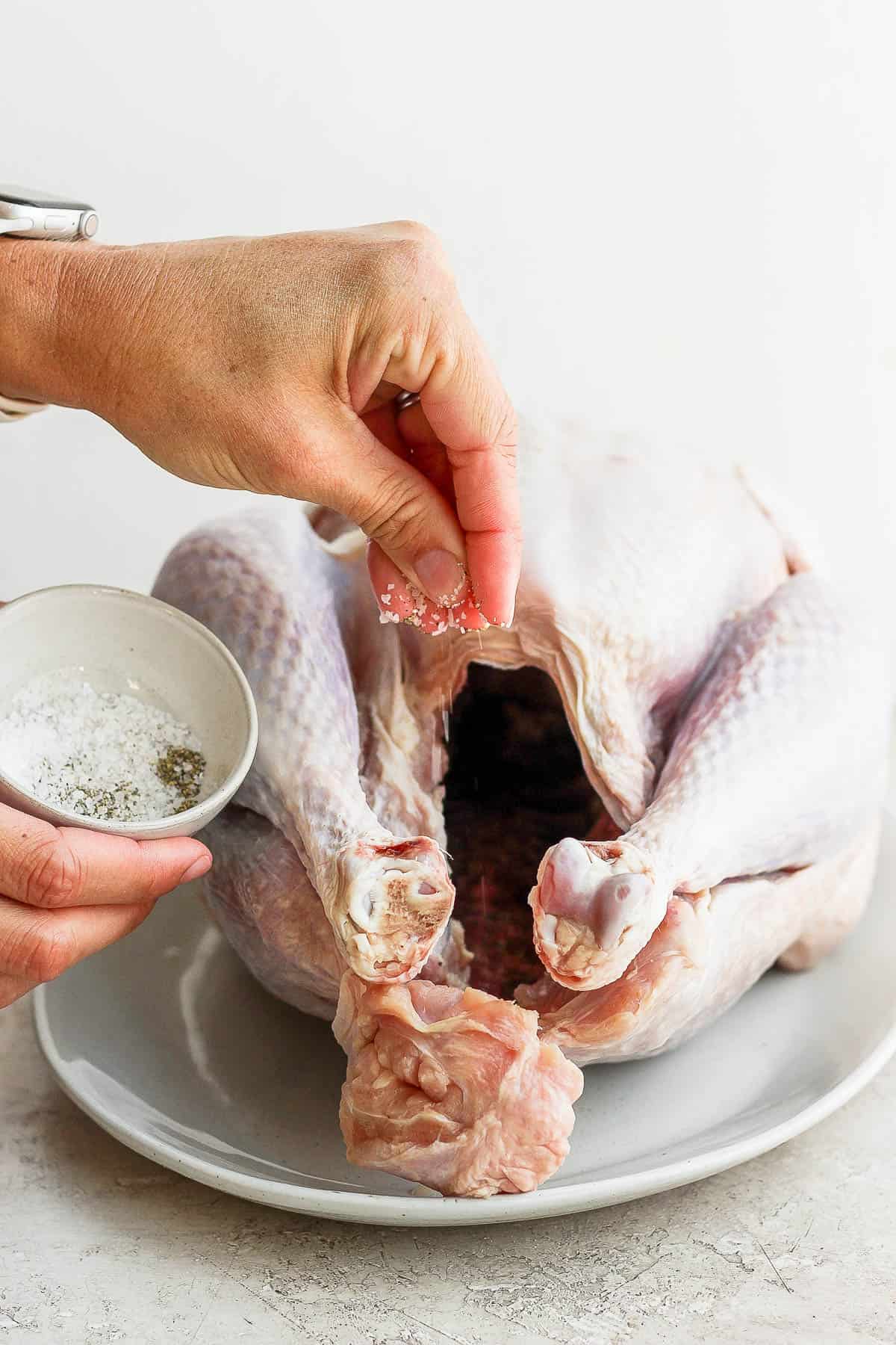 Salt and pepper being sprinkled in the turkey cavity.