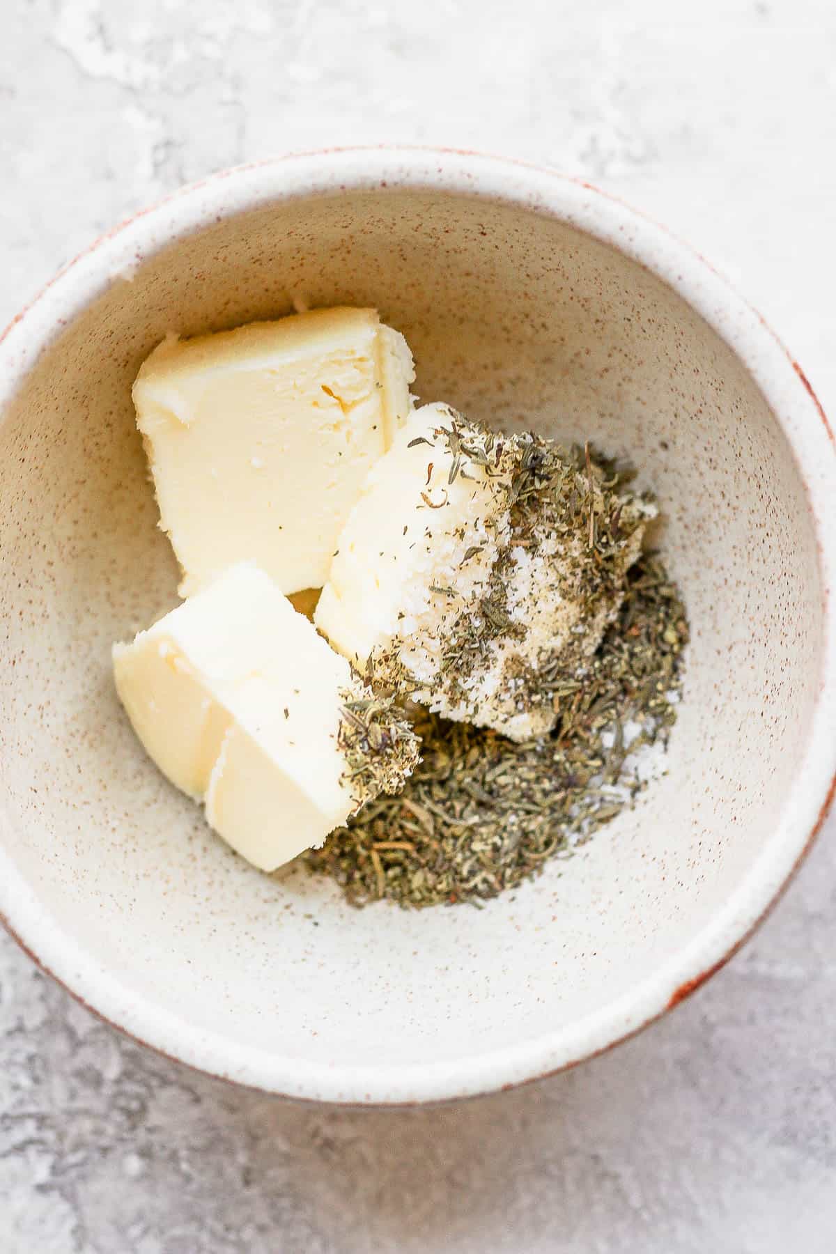 A bowl of softened butter and herbs.