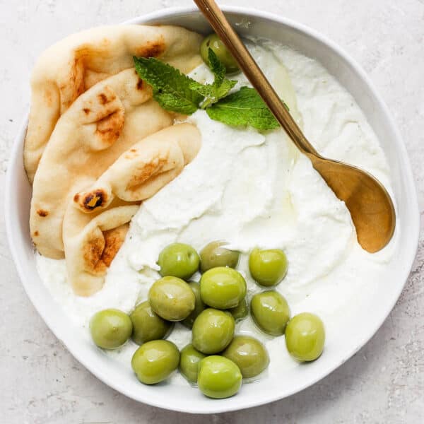 Bowl of whipped feta with some olive and pita bread.