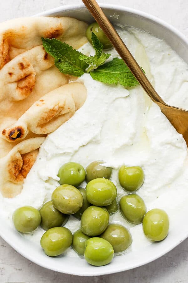 Bowl of whipped feta with some olive and pita bread.