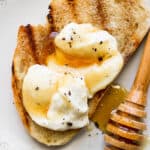 Grilled bread with whipped ricotta on top and some honey on a plate.