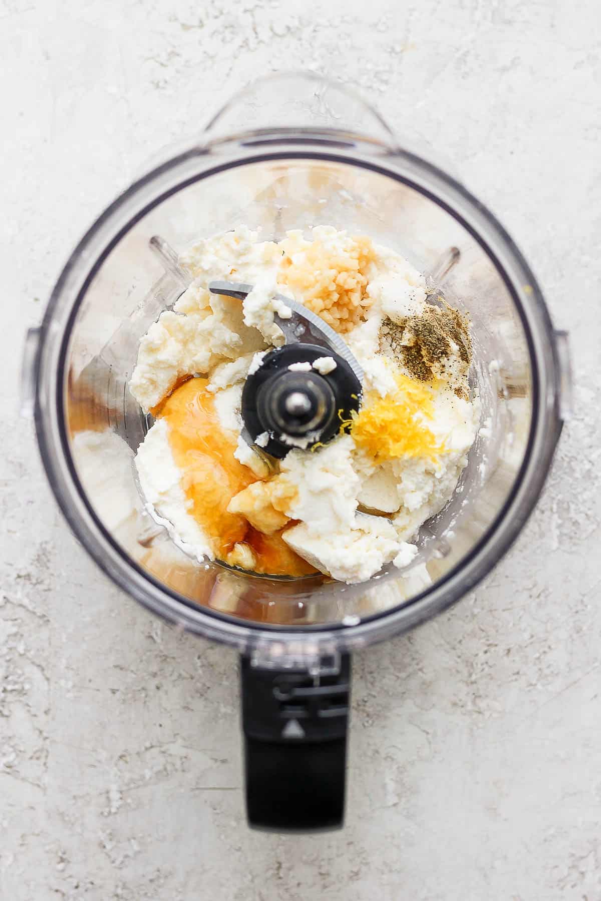 Ingredients for whipped ricotta in a food processor.