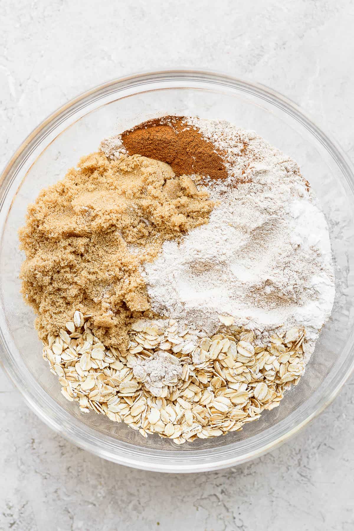 Flour, rolled oats, baking soda, baking powder, salt, brown sugar and cinnamon in a bowl.